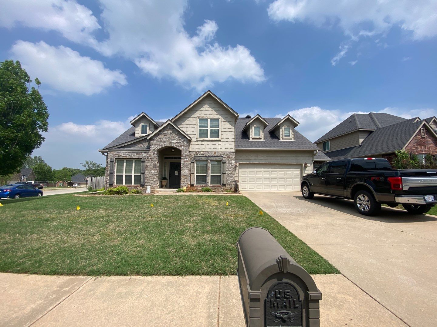 Completed roof replacement on a Sand Springs stone craftsman-style home with dormers