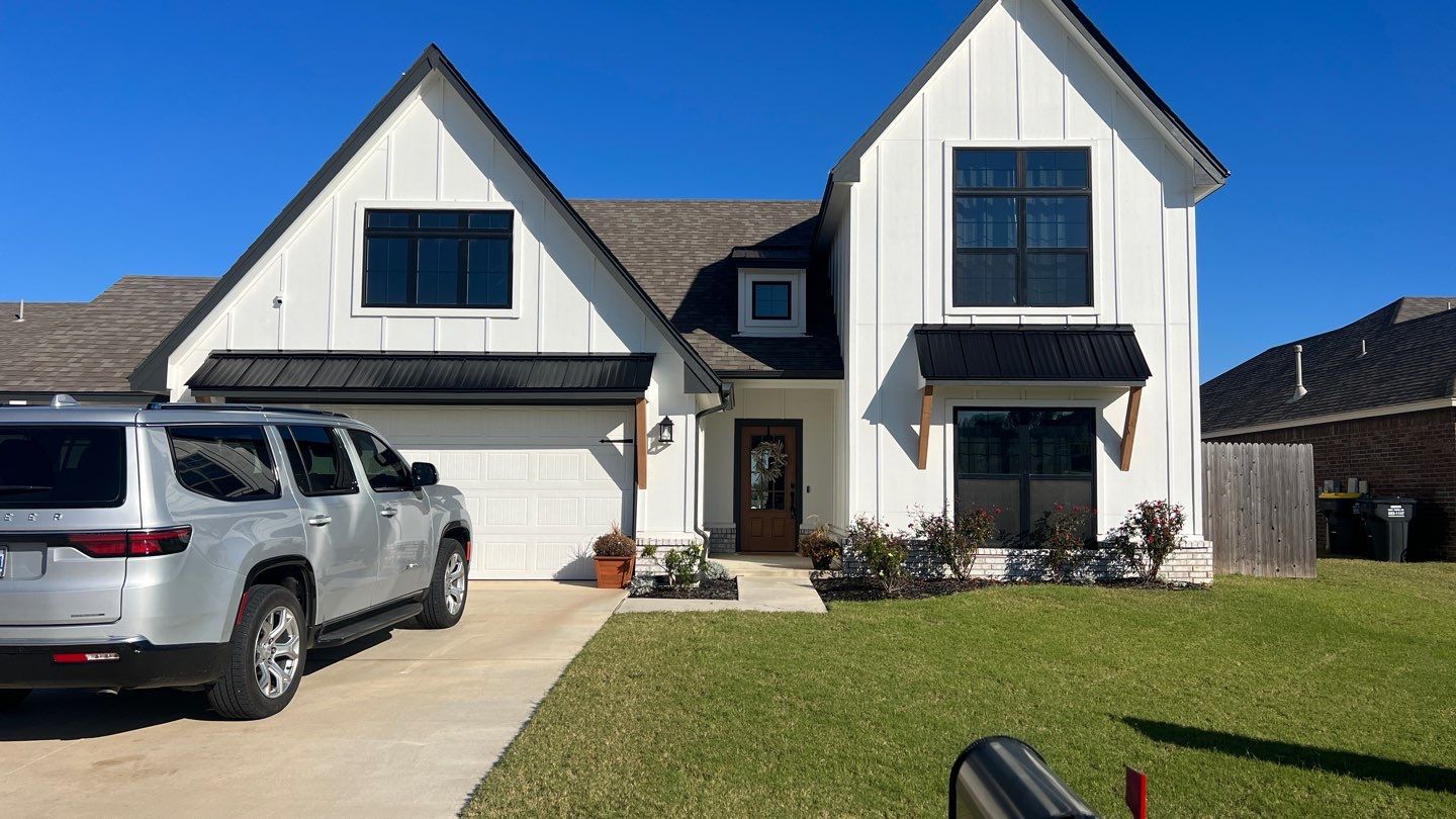 Completed FireHouse Roofing roof replacement on a Glenpool white modern farmhouse with dark architectural shingles and black metal accent roofs