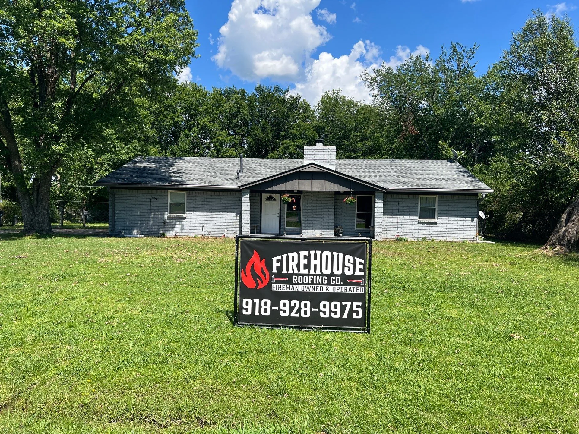 Completed roof replacement on a Claremore home with a FireHouse Roofing yard sign