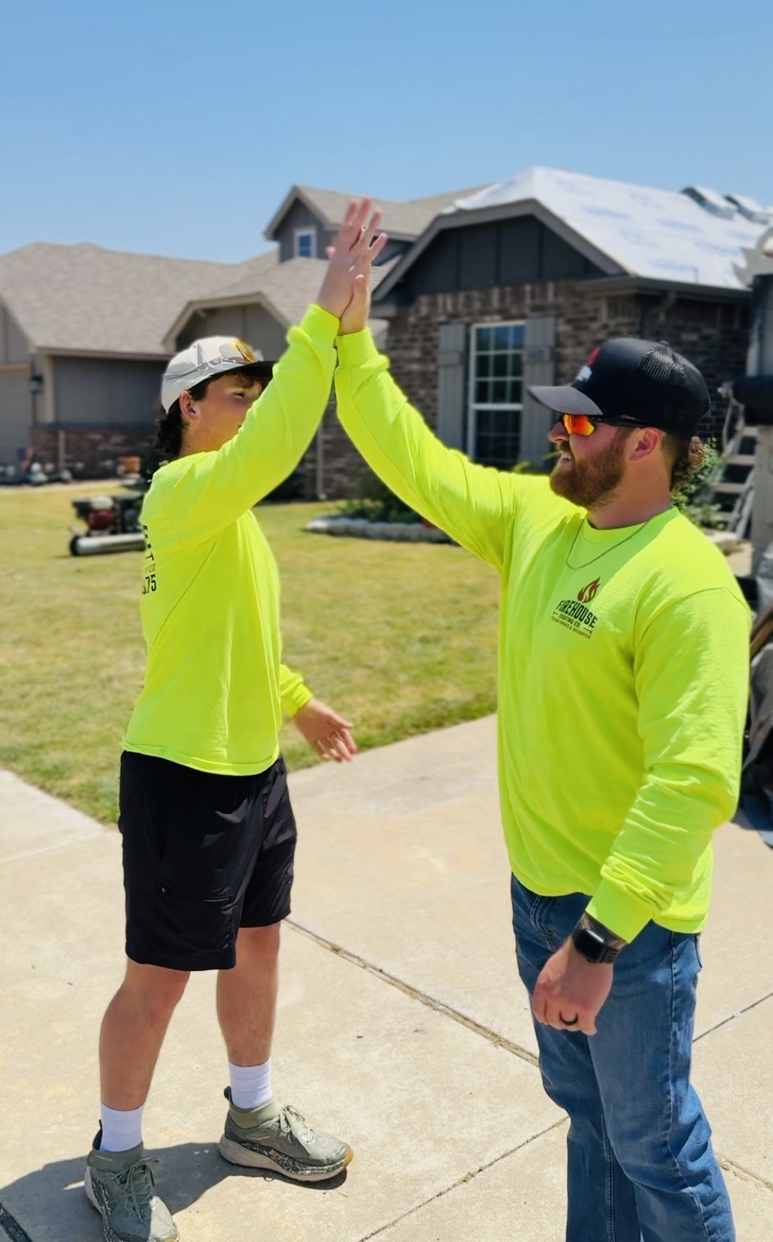 Two FireHouse Roofing crew members high-fiving on a job site