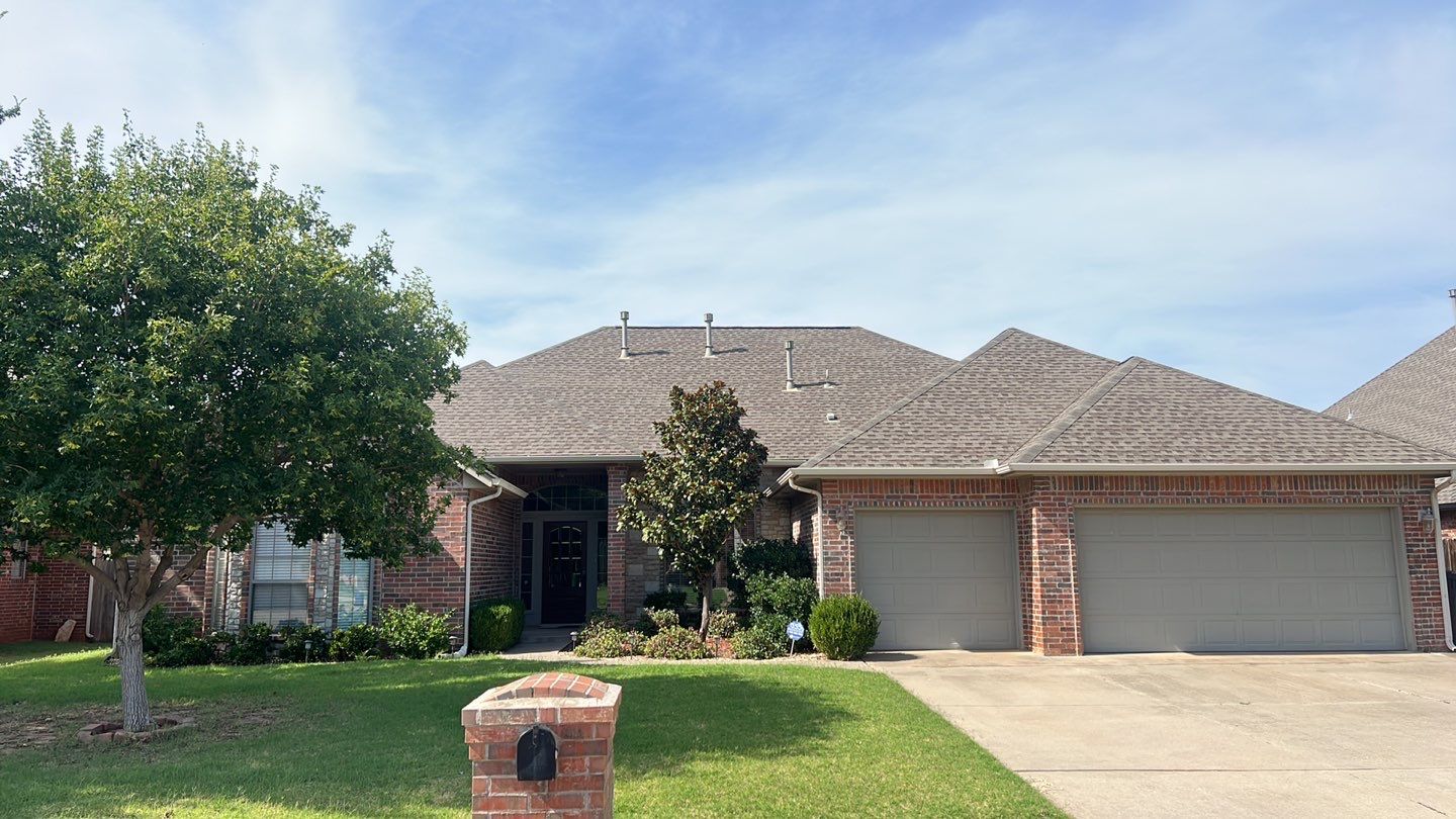 Completed FireHouse Roofing roof replacement on a brick home framed by mature trees