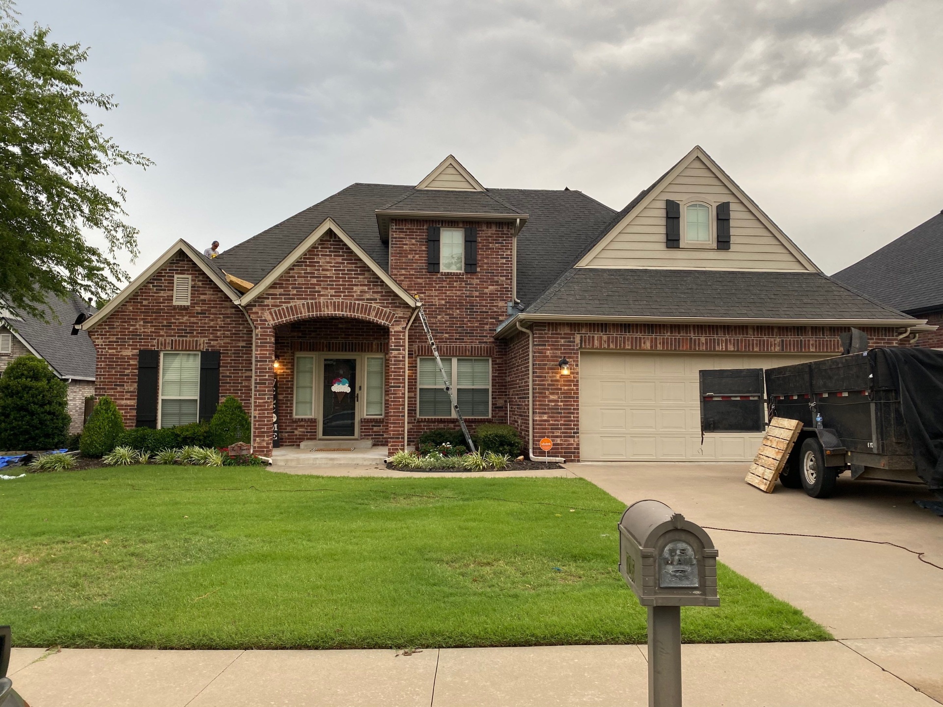 Completed roof replacement on a Sand Springs two-story brick home with dark architectural shingles