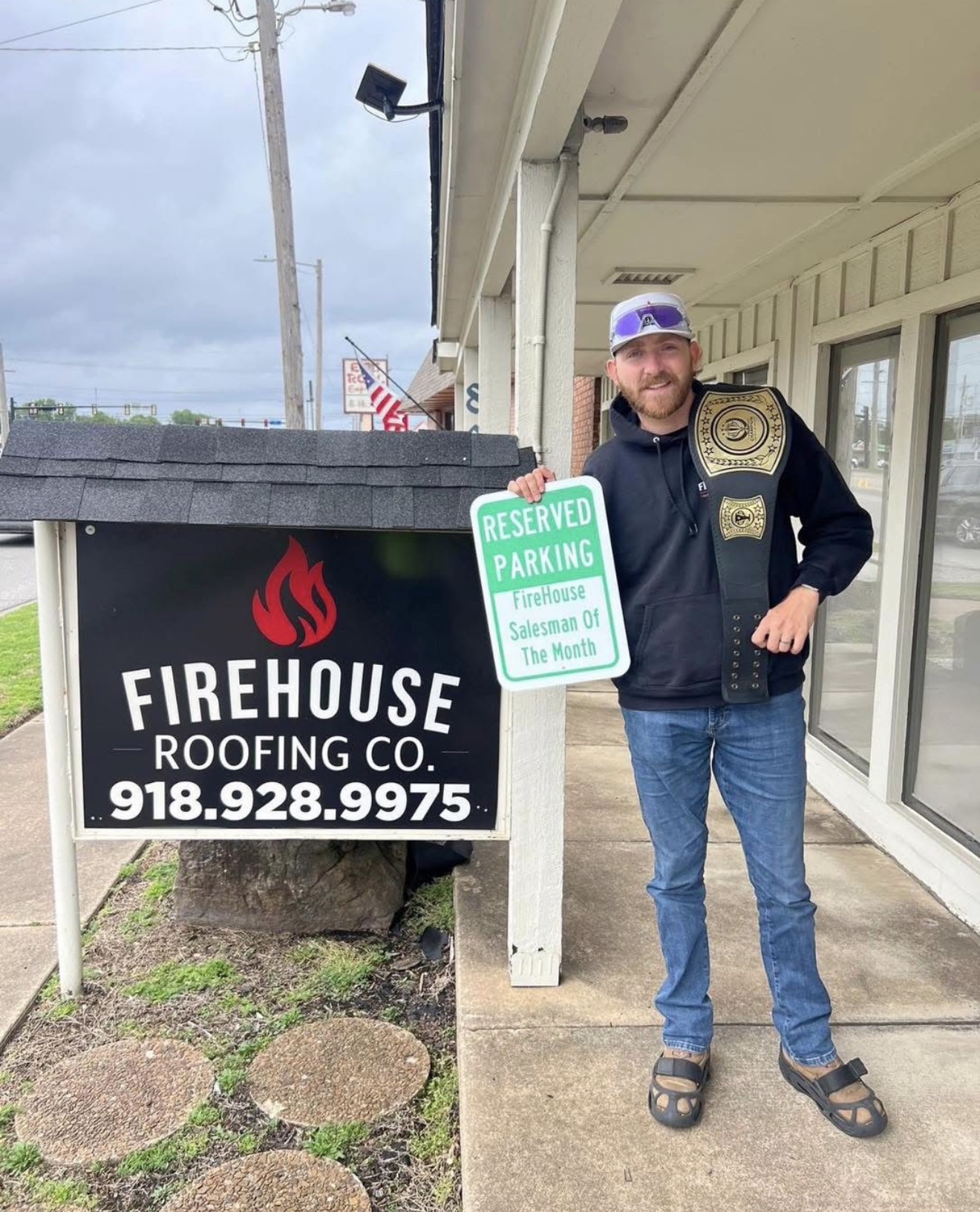 FireHouse Roofing Salesman of the Month standing by the company sign in Broken Arrow, Oklahoma