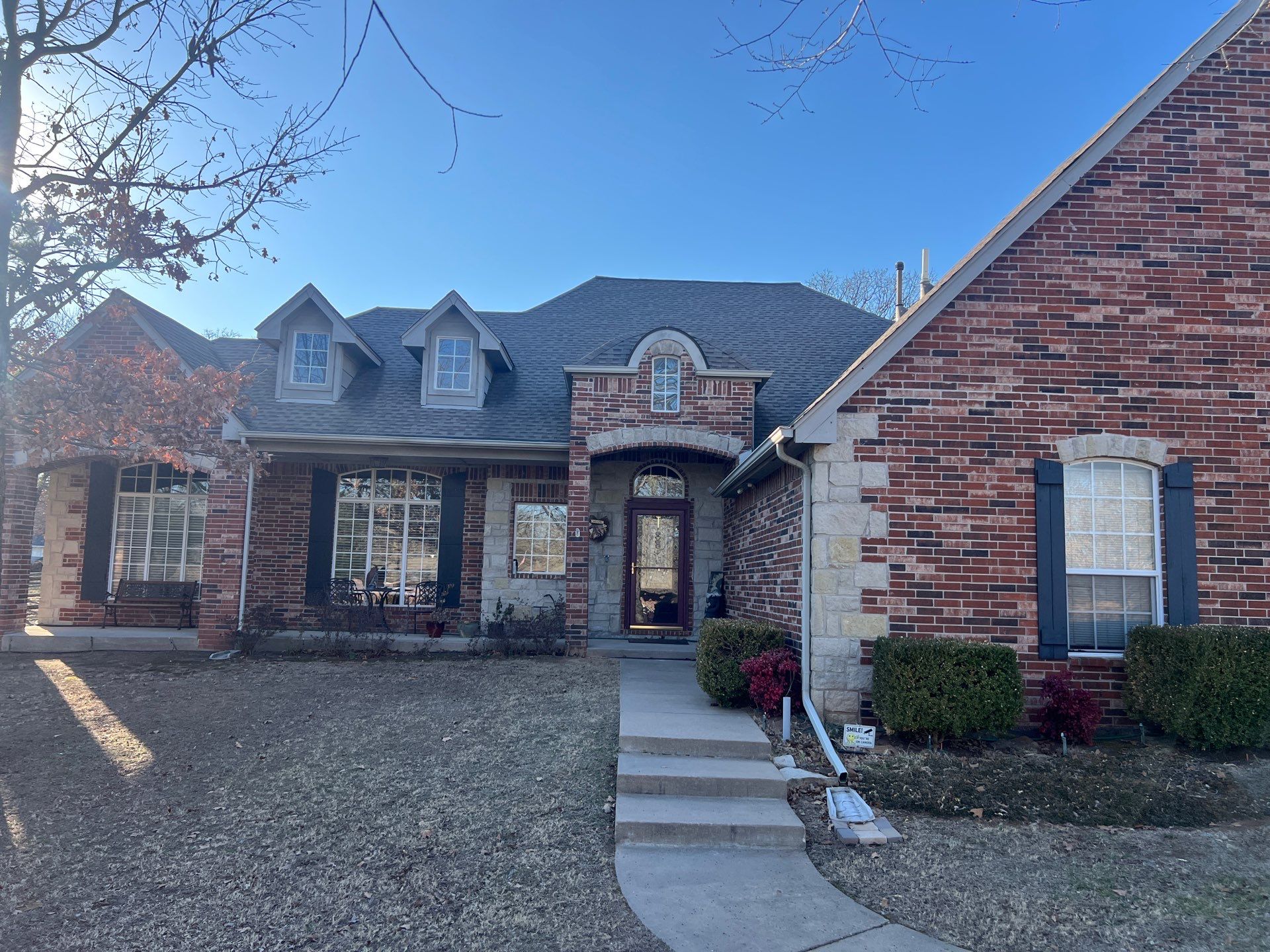 Completed FireHouse Roofing roof replacement on a Catoosa brick and stone home with dormers