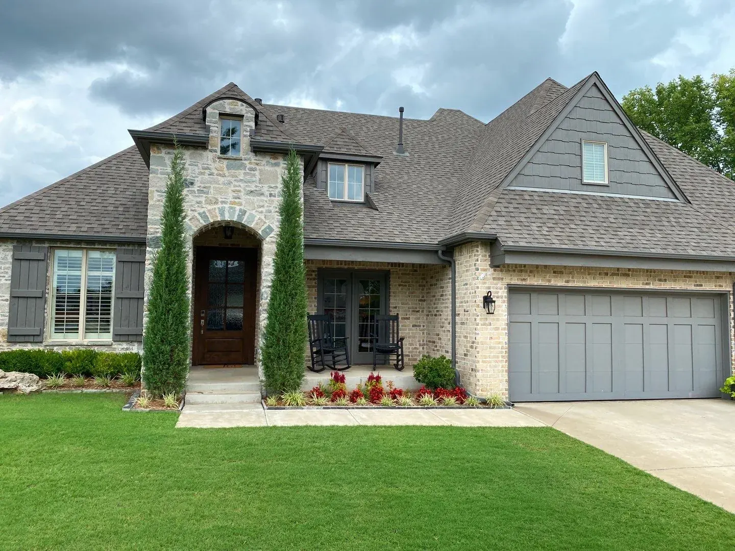 Completed roof replacement on a Bixby stone and brick home with brown architectural shingles