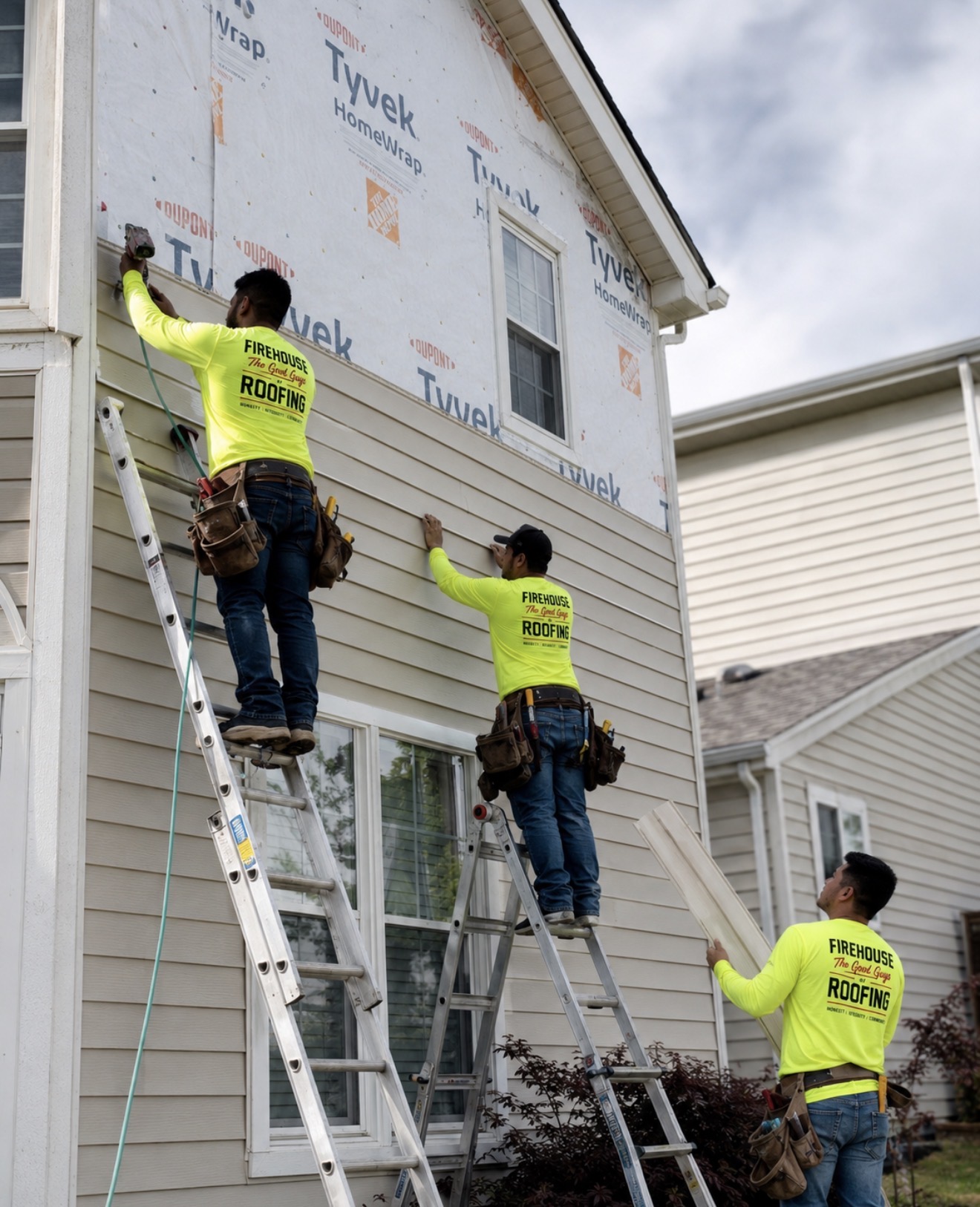 Crew laying fresh lap siding over Tyvek HomeWrap on a two-story home.