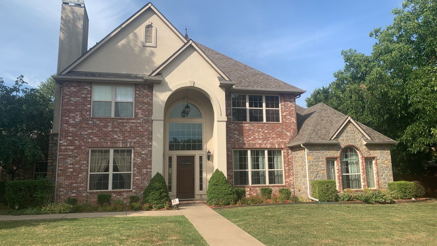 Completed roof replacement on a large two-story Catoosa brick and stucco home
