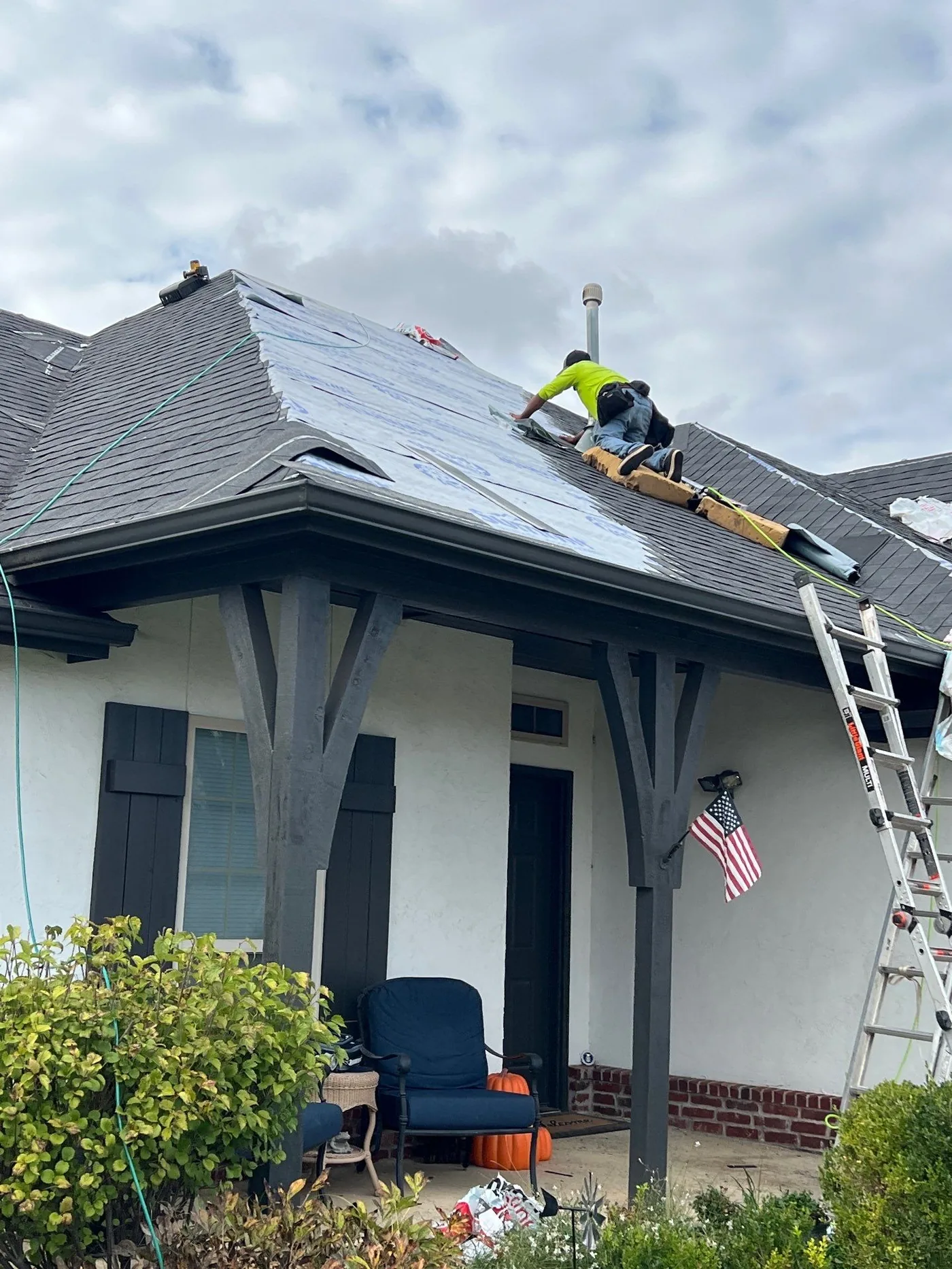 FireHouse Roofing crew member installing underlayment over a Tulsa porch roof during a tear-off