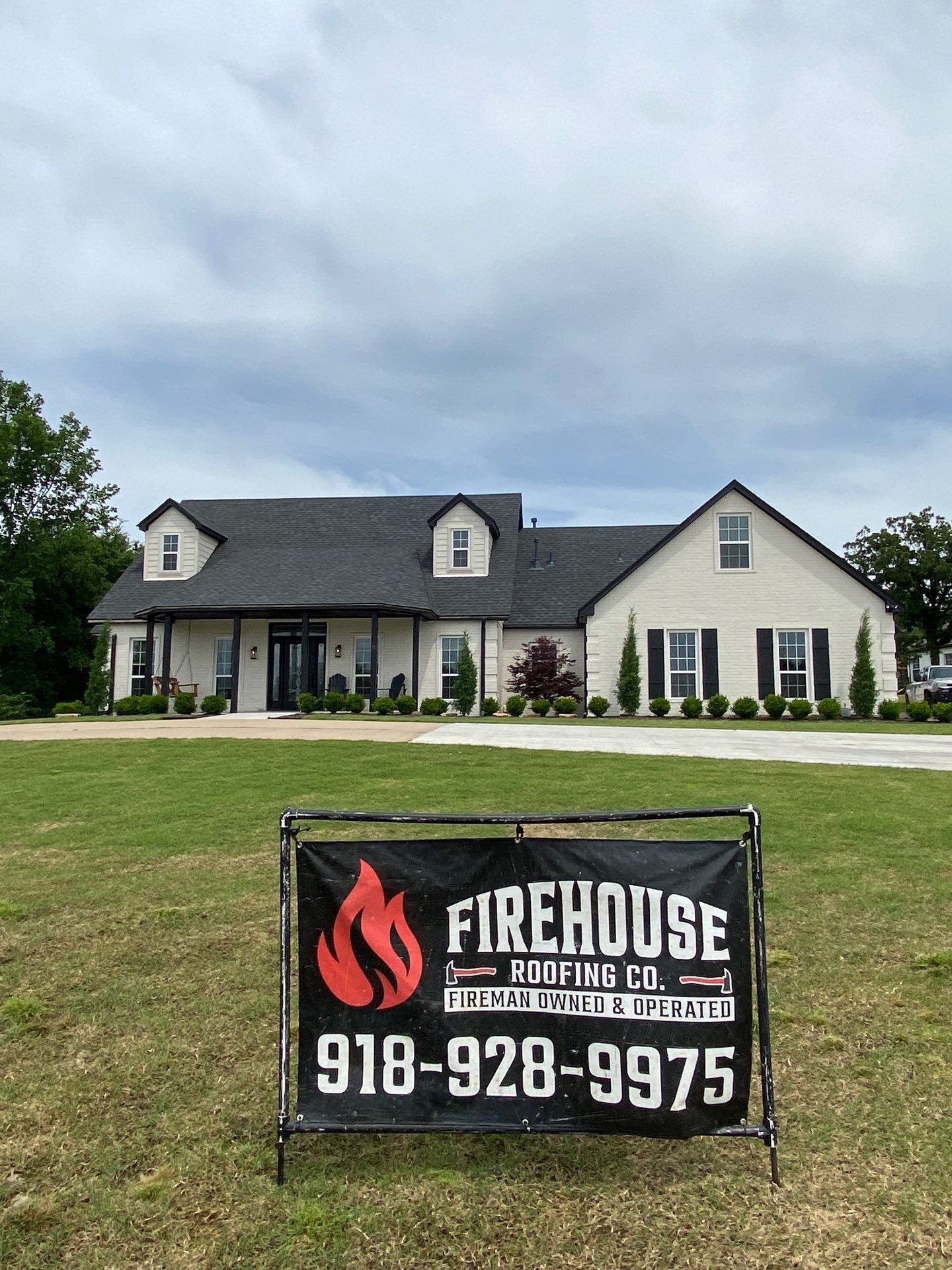 Completed FireHouse Roofing roof replacement on a Sapulpa white craftsman-style home with dark architectural shingles and a FireHouse yard sign