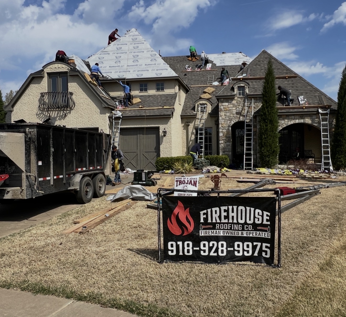 FireHouse Roofing crew actively replacing a roof on a Jenks home with the FireHouse yard sign in the foreground