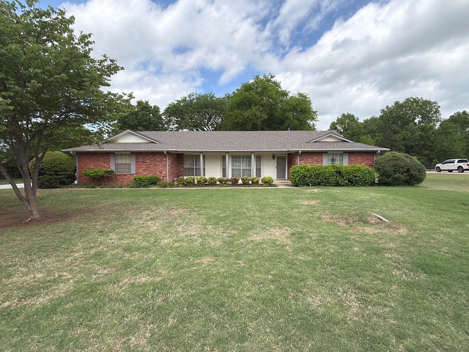 Completed roof replacement on a Catoosa brick ranch home with mature trees