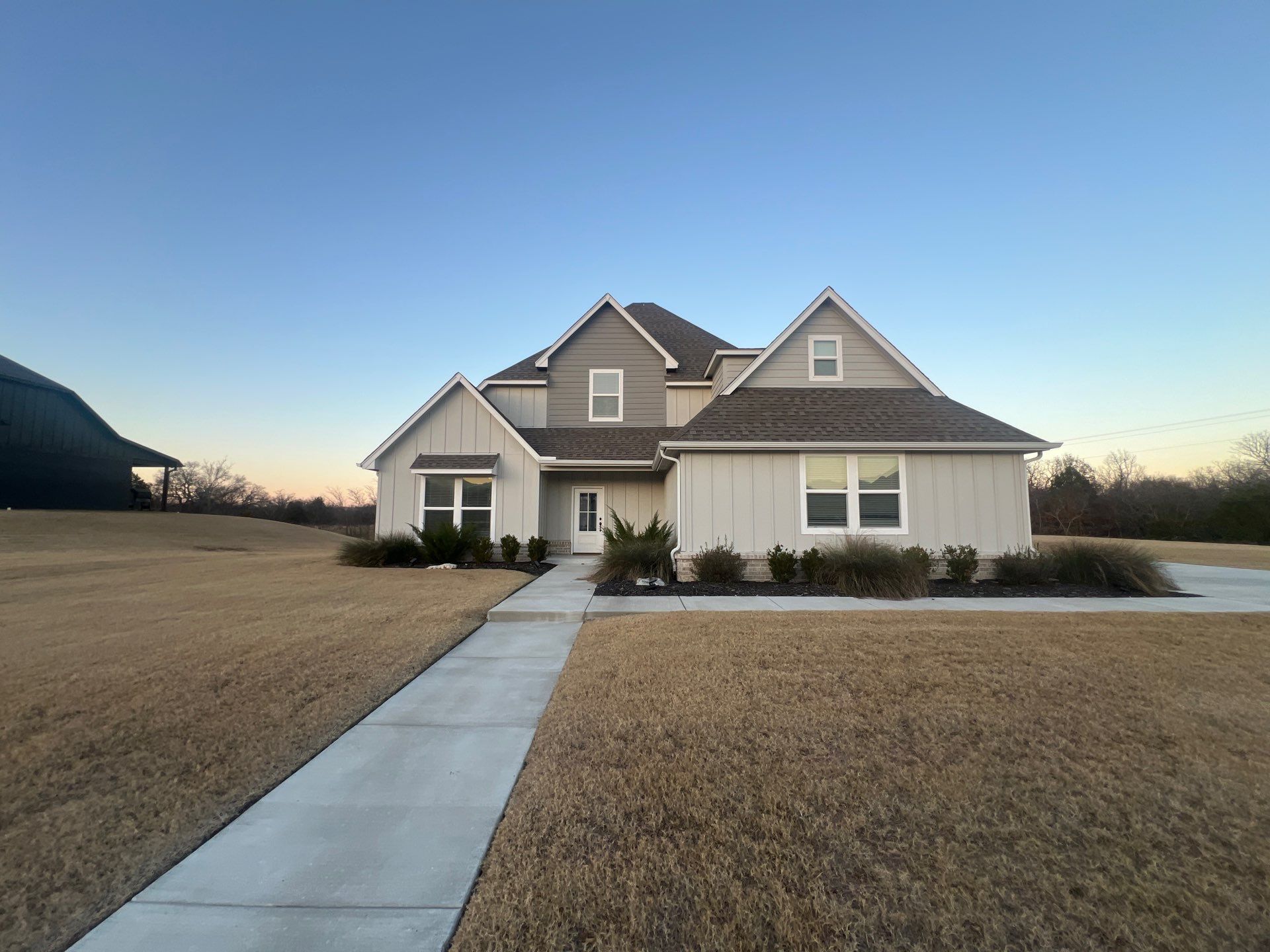 Completed roof replacement on a Catoosa modern farmhouse home at twilight
